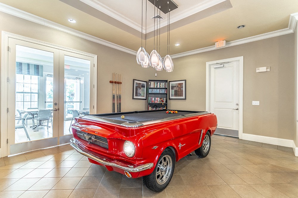 a red pool table with a black top in the middle of the room